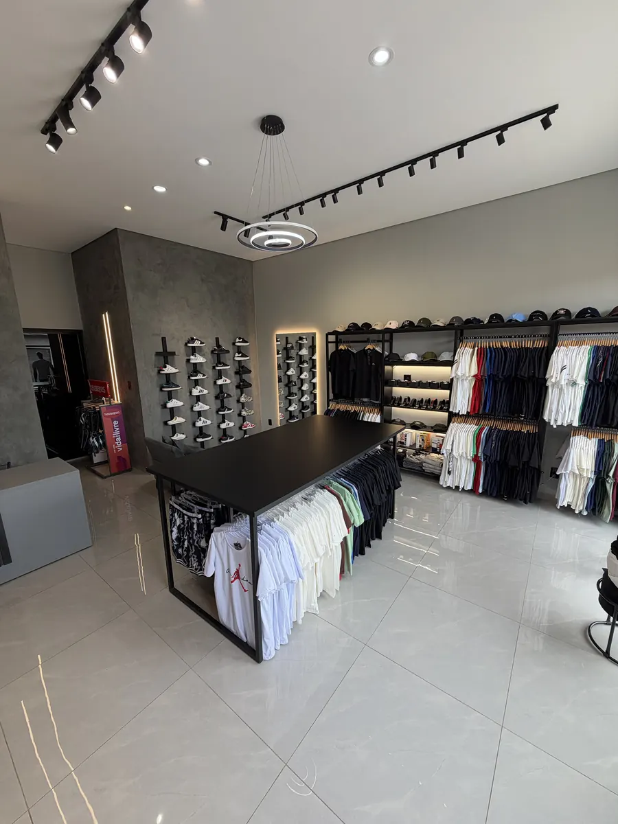 Interior da loja com mesa central, parede de tênis e iluminação em trilho