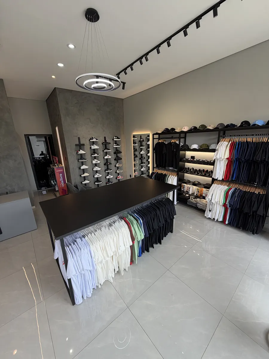 Mesa central com camisetas penduradas por cor